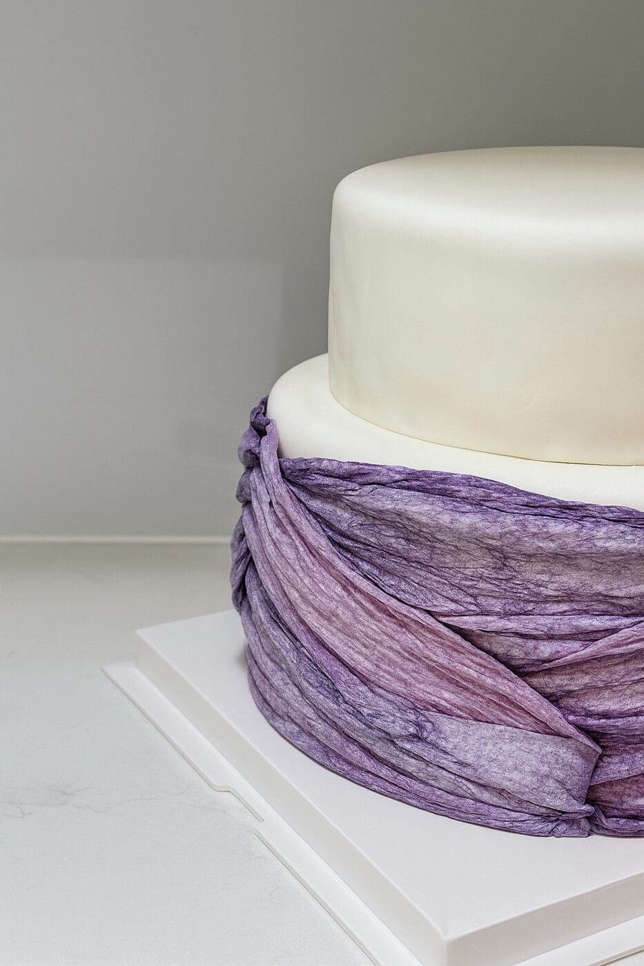 Close detail of a wedding cake wrapped in hand-dyed lilac silk