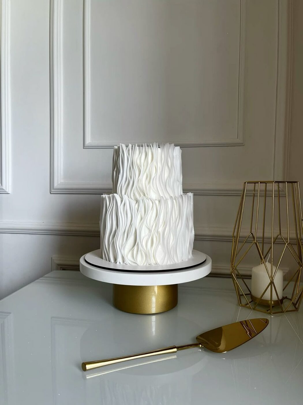 Long fluted wedding cake with roses and tapered silver candles