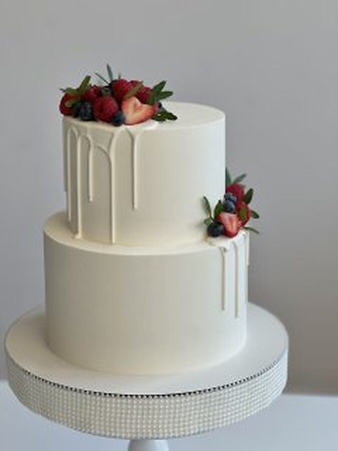 Two-tier wedding cake with white drip and fresh berries