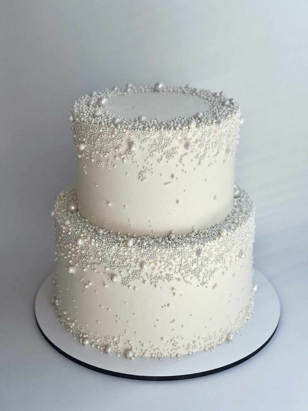 Long white wedding cake with piped waves and white roses
