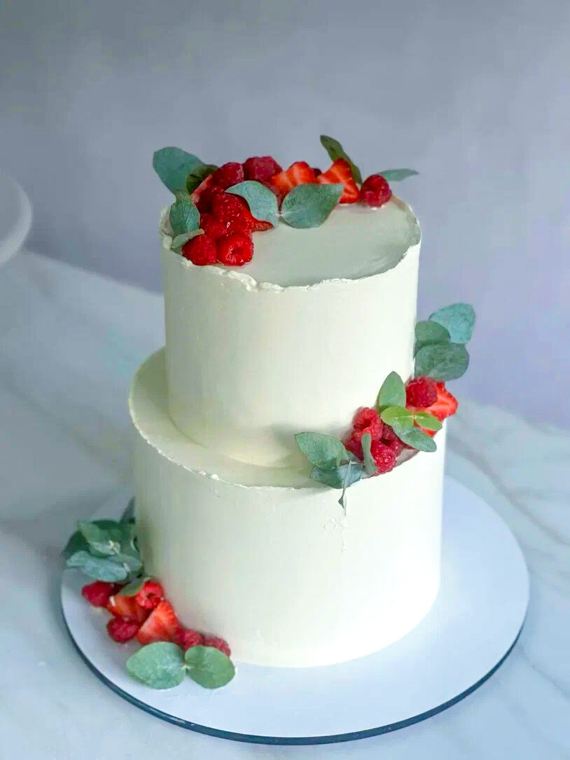 Two-tier wedding cake with berries and eucalyptus