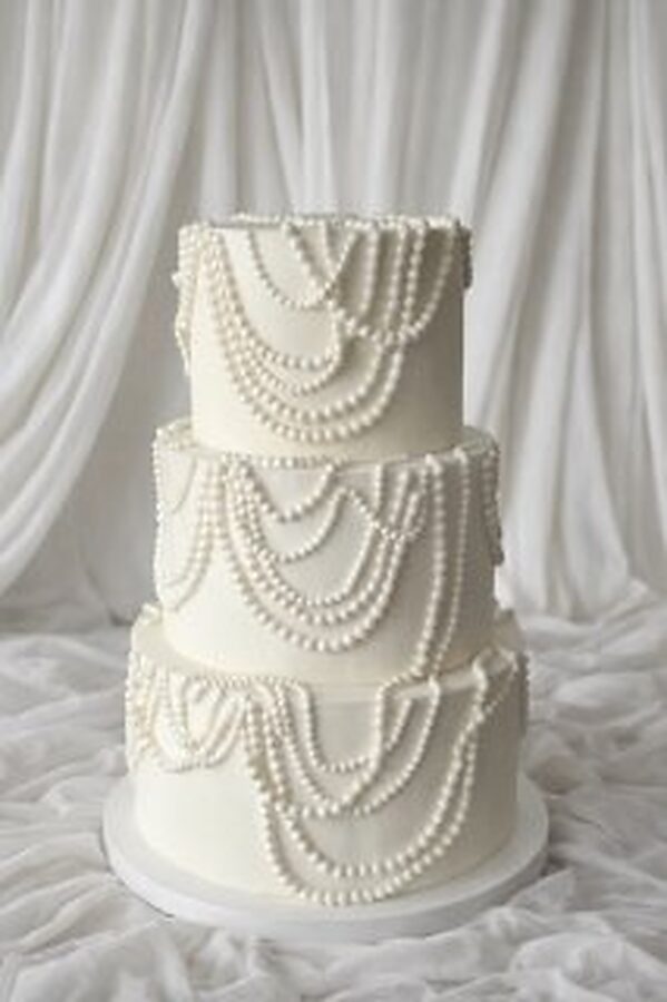 Three-tier wedding cake draped in sugar pearl swags