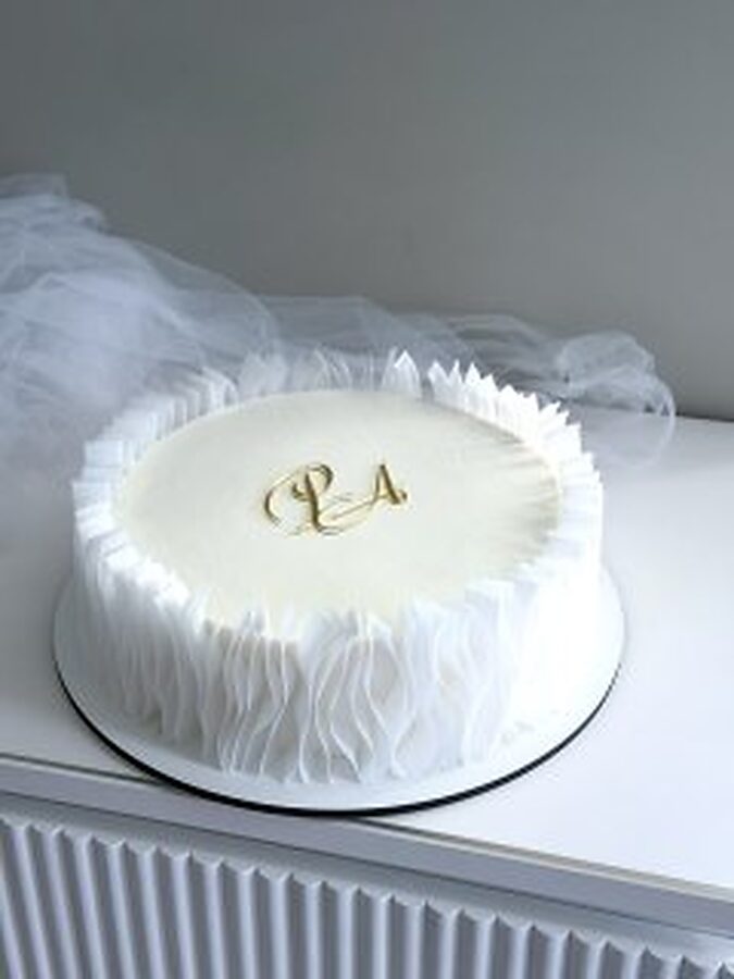 Ruffled wedding cake finished with a gold monogram