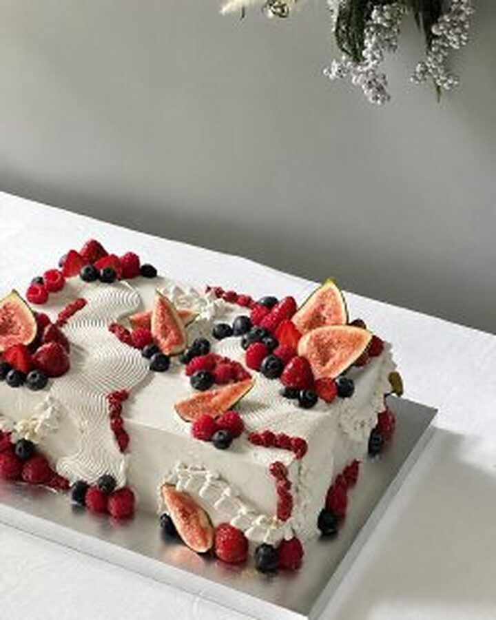 Long cake piped with cream and dressed with figs and berries