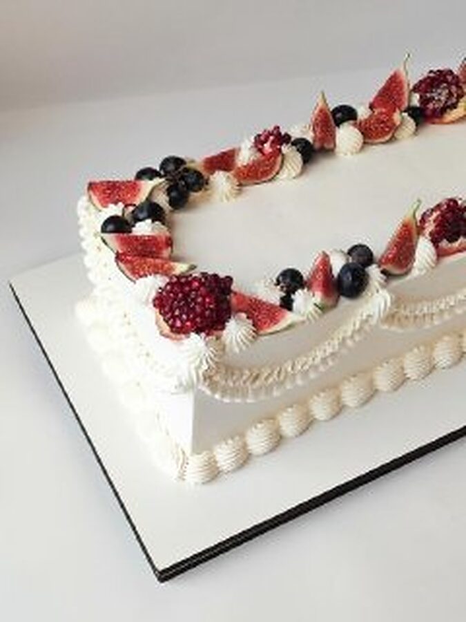 Long cake decorated with figs, pomegranate and berries