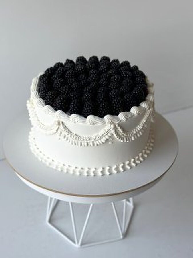 Round cake with piped scallops and blackberries