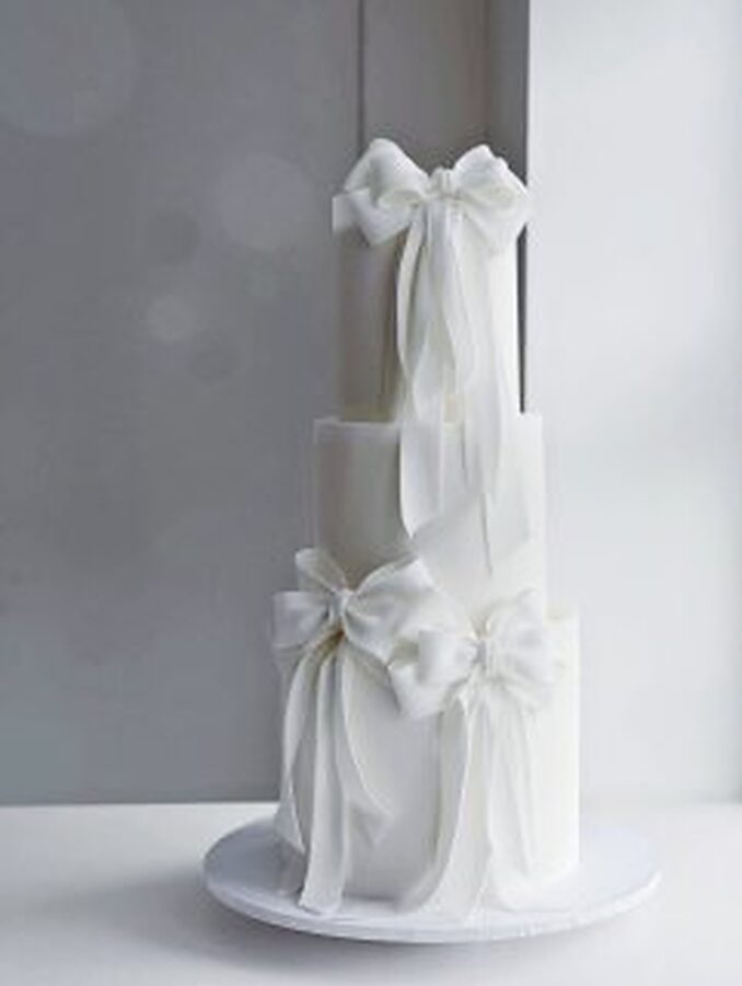 Tall three-tier wedding cake finished with sugar bows
