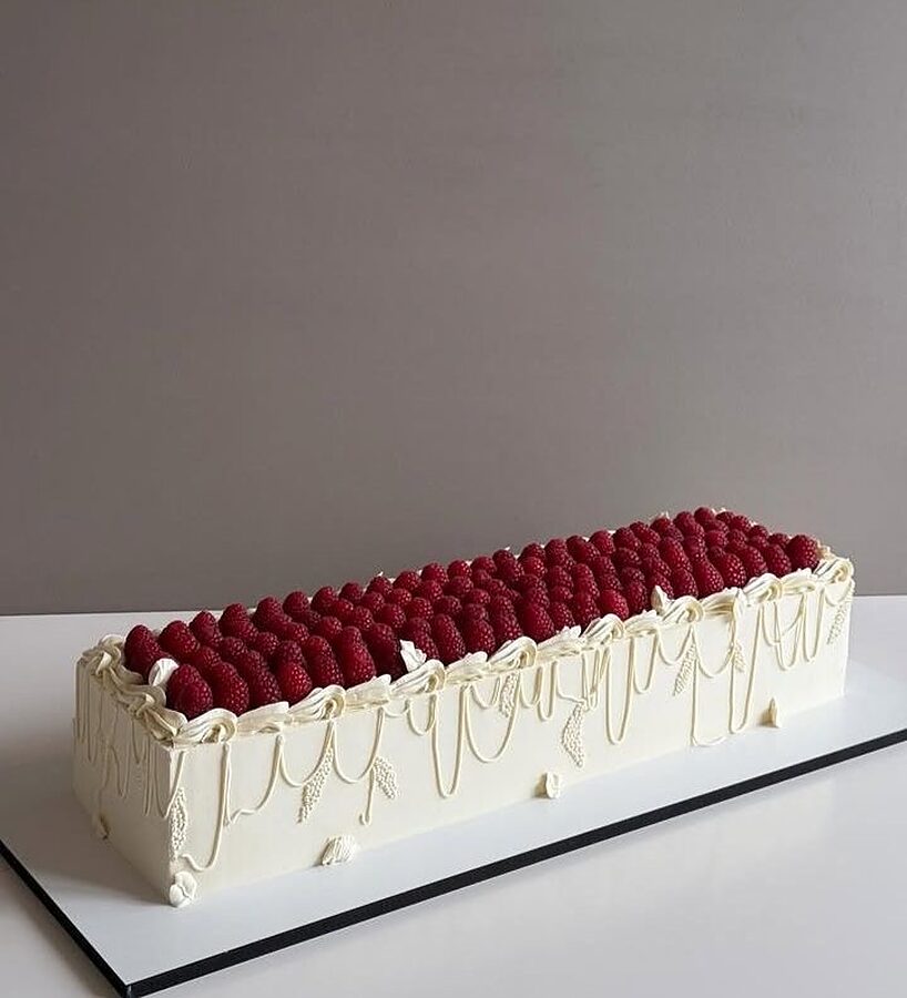 Long celebration cake with raspberries and piped cream