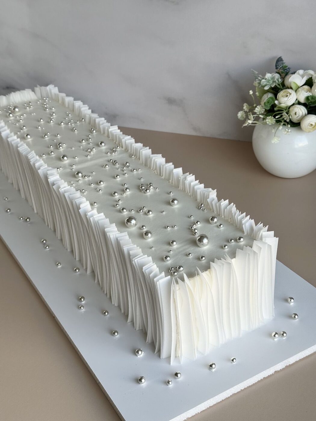 Long pleated wedding cake finished with silver pearls