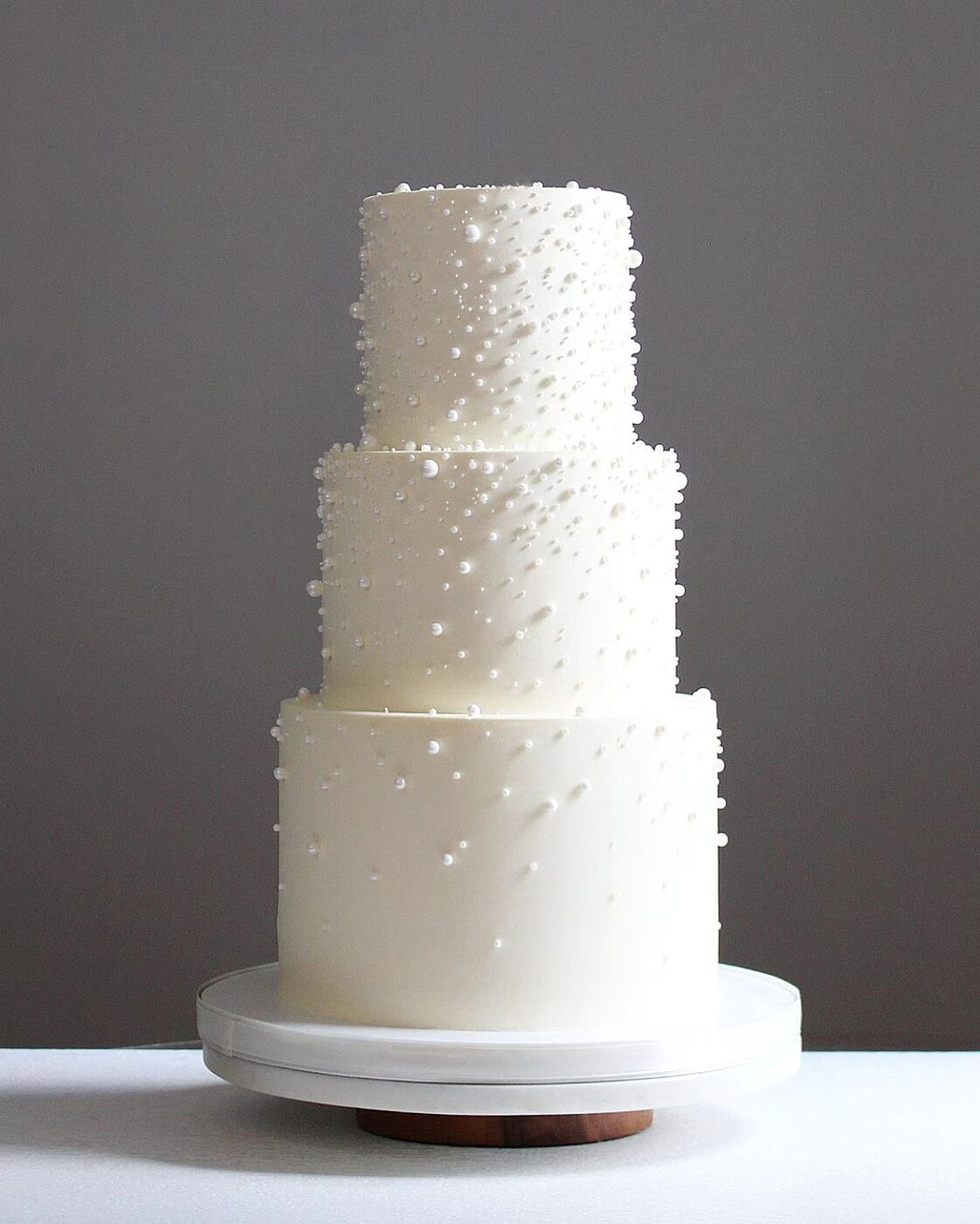 Three-tier white wedding cake scattered with sugar pearls