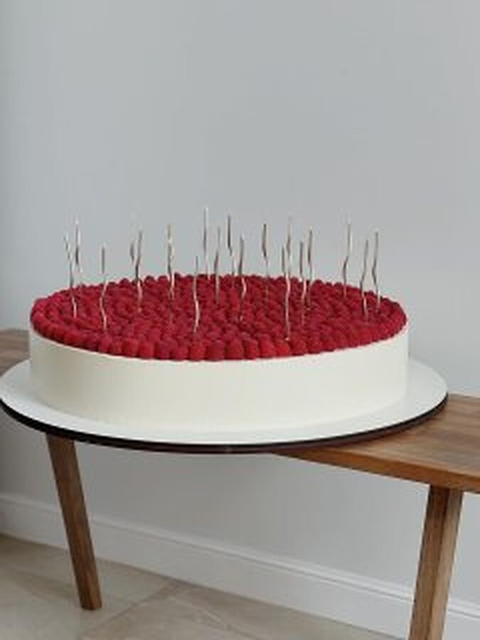 Raspberry-topped cake with slim silver candles